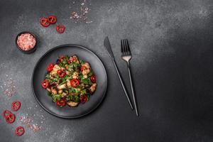 A salad of baked aubergine, sweet pepper, garlic, zucchini and parsley in a black plate photo
