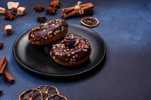 Pastries concept. Donuts with chocolate glaze with sprinkles, on a dark concrete table photo