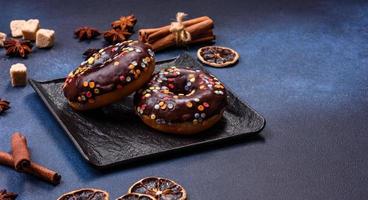 Pastries concept. Donuts with chocolate glaze with sprinkles, on a dark concrete table photo