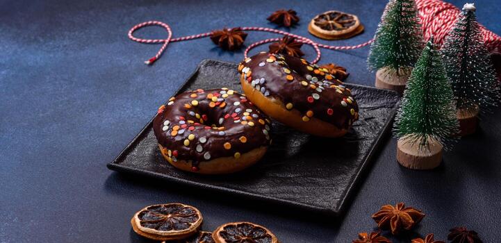 concepto de pasteles. donuts con glaseado de chocolate con chispas, sobre una mesa de hormigón oscuro foto