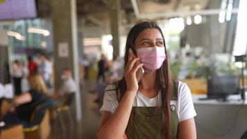 kvinna bär mask på restaurang, samtal på de telefon video