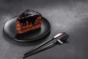 A piece of fresh delicious cake with nuts and chocolate on a black plate photo