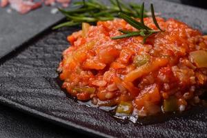 arroz hervido con pimientos, especias, hierbas y salsa de tomate en un plato de pizarra negra