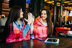 Two young and beautiful girls having fun in cafe photo