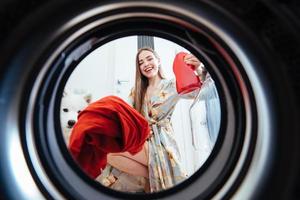 mujer joven en casa pone el vestido en la secadora. foto