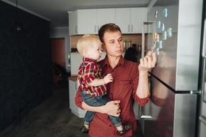 Dad and little son in the kitchen by the fridge photo
