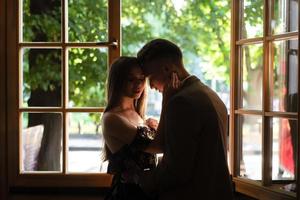 joven pareja enamorada de pie junto a la ventana foto