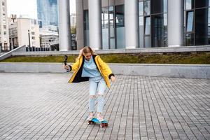 Blond female hipster woman riding on the longboard in the street at city. photo