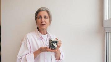 Woman drinks tea from a mug and talks to camera video