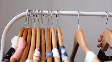 Person browsing clothes hanging on a rack video