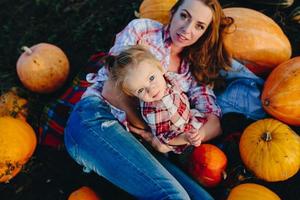 mother and daughter lie between pumpkins photo