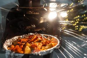 Baked potatoes with carrot and other spices in roasting pan. photo