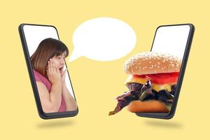mujer gorda en la pantalla táctil del teléfono inteligente negro que quería comer la hamburguesa que estaba en el teléfono. concepto de tecnología que vende productos en línea a través de la entrega a domicilio por Internet. trazado de recorte foto