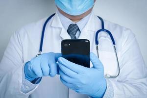 Doctors wearing masks and gloves are pressing mobile phones to contact. Concept of healthcare services and medical technology. Maintain check for coronavirus photo