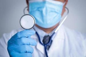 Doctors wearing masks and blue gloves. Hold a stethoscope to examine the patient. Medical care service concept, cure coronavirus. Copy space photo