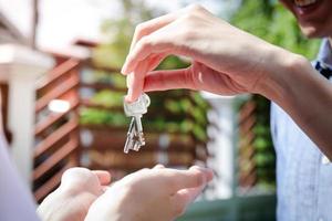 las parejas asiáticas compran casas para estar juntas. los hombres dan las llaves de la casa a las mujeres. el concepto de formar una familia feliz. concepto de negocio inmobiliario foto