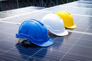 A safety helmet to prevent head bumps during work, a blue, white, yellow mechanic is placed on the solar panel. Concept of energy technology, work. copy space