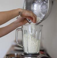 mujer vertiendo requesón en una licuadora en la cocina foto