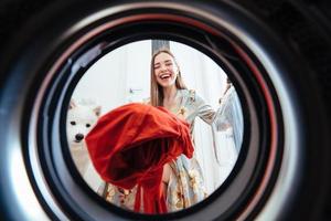 mujer joven en casa pone el vestido en la secadora. foto