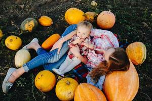 mother and daughter lie between pumpkins photo