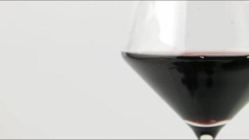 Rotwein. Gießen von Rotwein in ein Glas aus der Flasche auf dem weißen Hintergrund. video