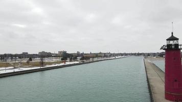 antenne visie van vuurtoren in kenosja, Wisconsin, Aan meer Michigan. licht sneeuw vallen in de park. kalmte wateren in de kanaal. sculpturen in de park aan de overkant kanaal. video