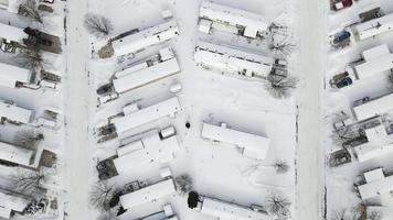dall'alto al basso video di un' mobile casa parco coperto nel neve chiaramente mostrando un' numero di Aperto molti. Questo è un ordinato ma corri giù parte di cittadina.