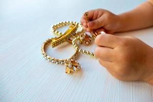 las manos de los niños juegan con joyas de oro y bisutería, sobre fondo blanco. concepto de felicidad de las mujeres foto