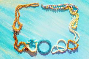 A set of natural jewelry. Space for the text. Coral amber pearl and bone jewelry on a blue background. Top view. photo