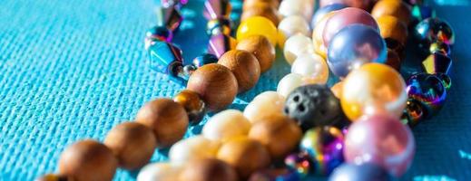 Heap of colored bright jewelry beads on a blue background. Different gems beads necklace. Jewel necklace modern fashion pattern or texture. copy space. photo