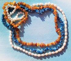 A set of natural jewelry. Space for the text. Coral amber pearl and bone jewelry on a blue background. Top view. photo