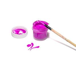 A jar of acrylic paints and a brush in paint. Purple paint. photo