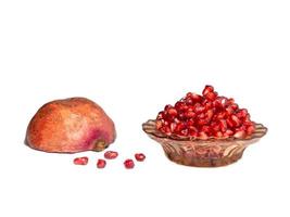 Plate with pomegranate seeds and half of pomegranate on white background photo