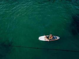 Mother with two daughters stand up on a paddle board photo