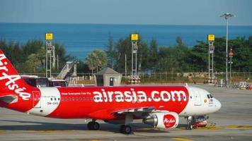 PHUKET, THAILAND NOVEMBER 22, 2018 - Low cost airline Airbus A320 of AirAsia at Phuket airport. Tractor tows the plane on the airfield. Tourism and aviation concept video