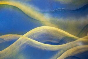 Blue abstraction and golden curves on plaster wall background. photo