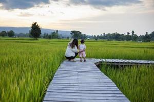 Mother and daughter doing activities together, walking to see the beautiful rice fields and mountains during the sunset time. photo