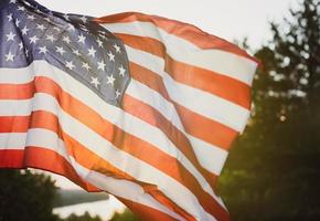 bandera del día de los veteranos de los estados unidos de américa. bandera estadounidense ondeando en el fondo del sol poniente en la naturaleza. foto