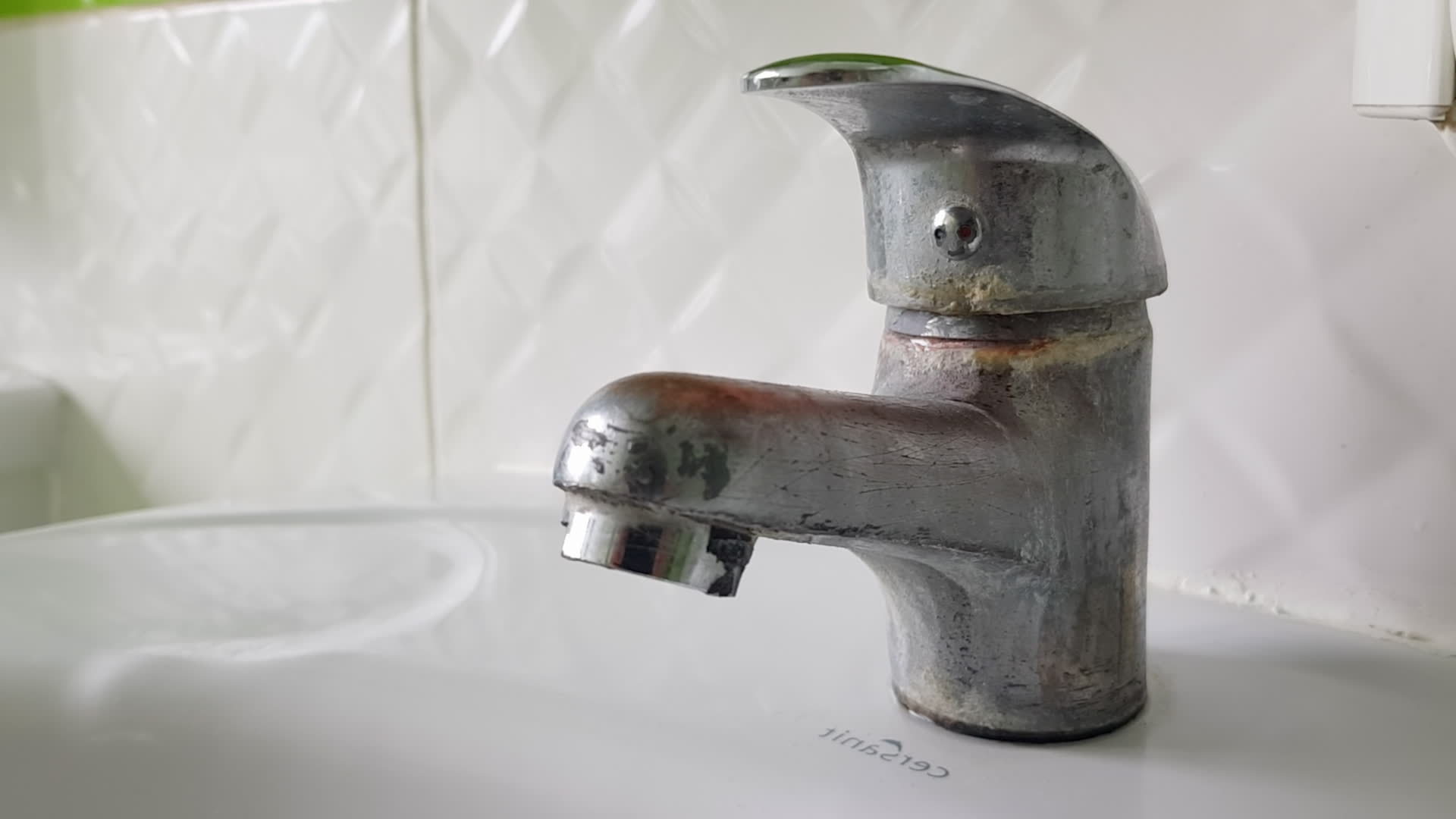 Old and dirty faucet and white ceramic sink. The concept of cleaning