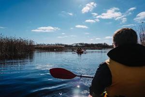 Group of people in kayaks among reeds on the autumn river. photo