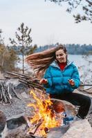 Happy young brunette girl sitting next to bonfire photo