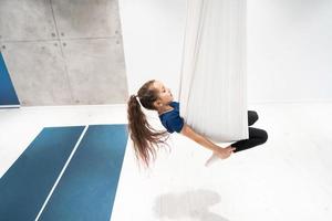 portrait of a beautiful young girl engaged in fly yoga on canvases. photo