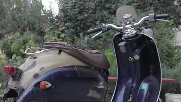 un scooter minable vintage ou une mini moto se tient à l'extérieur. mode de transport populaire. le volant d'un vieux cyclomoteur bleu avec un siège marron. Ukraine, Kyiv - 20 août 2021. video