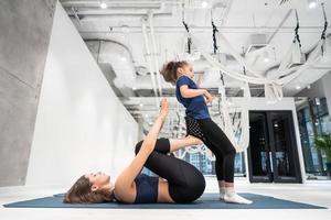 Young adult mother doing fitness with her little daughter photo