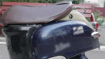 Vintage shabby scooter or mini motorcycle stands outdoors. Popular mode of transport. The steering wheel of an old blue moped with a brown seat. video