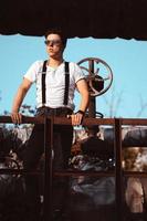 Guy in a shirt with suspenders posing at old pipes and valves photo