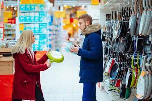 The guy and the girl choose pot and frying pan in a supermarket. photo