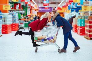 Young handsome guy rides a girl in a supermarket in a trolley photo