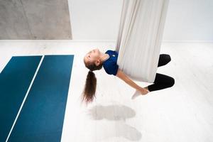 portrait of a beautiful young girl engaged in fly yoga on canvases. photo