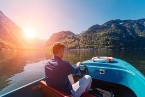 Handsome young guy controls a motorboat on a mountain lake photo